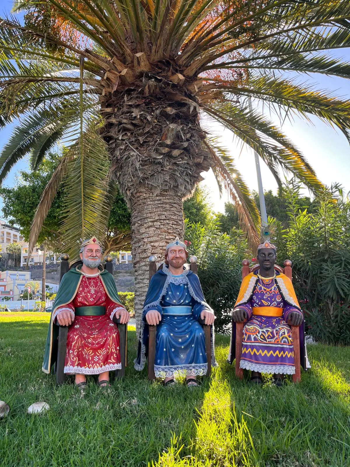 Imágenes religiosas a tamaño real de los tres Reyes Magos, sentados en sus tronos bajo una palmera